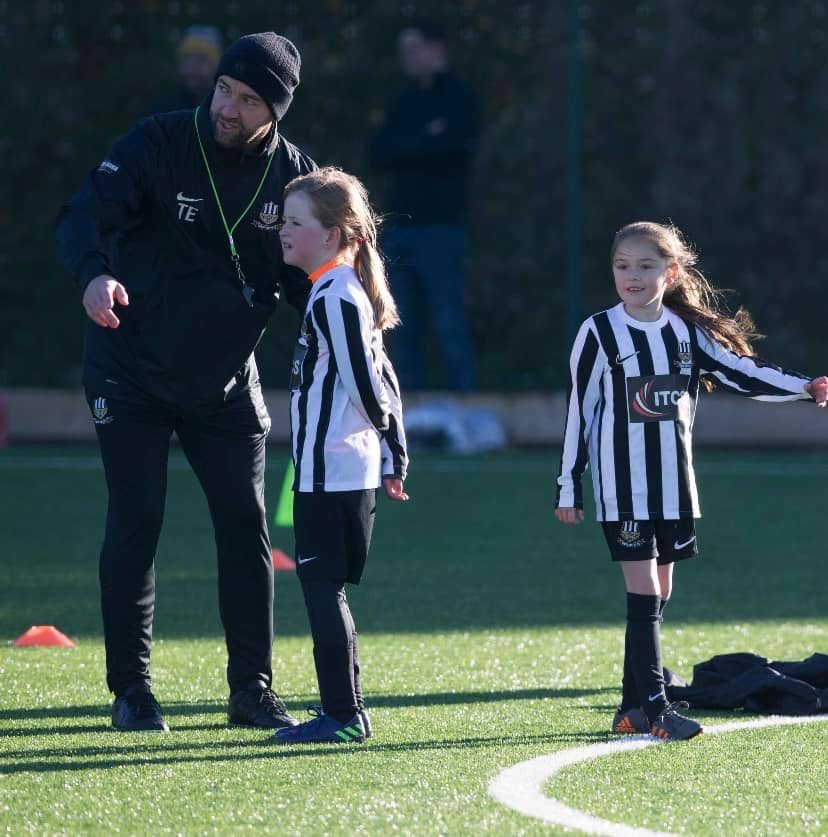 Tondu United FC coach with two young girl players on the pitch