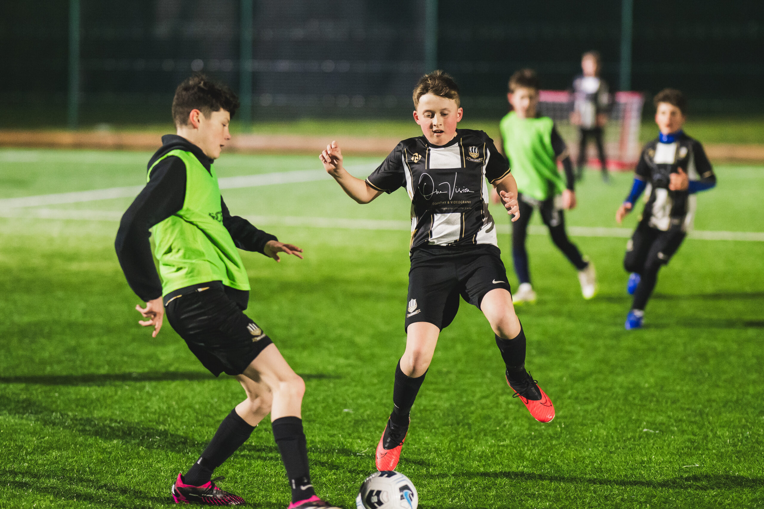 Two boy players with others in the background, playing football