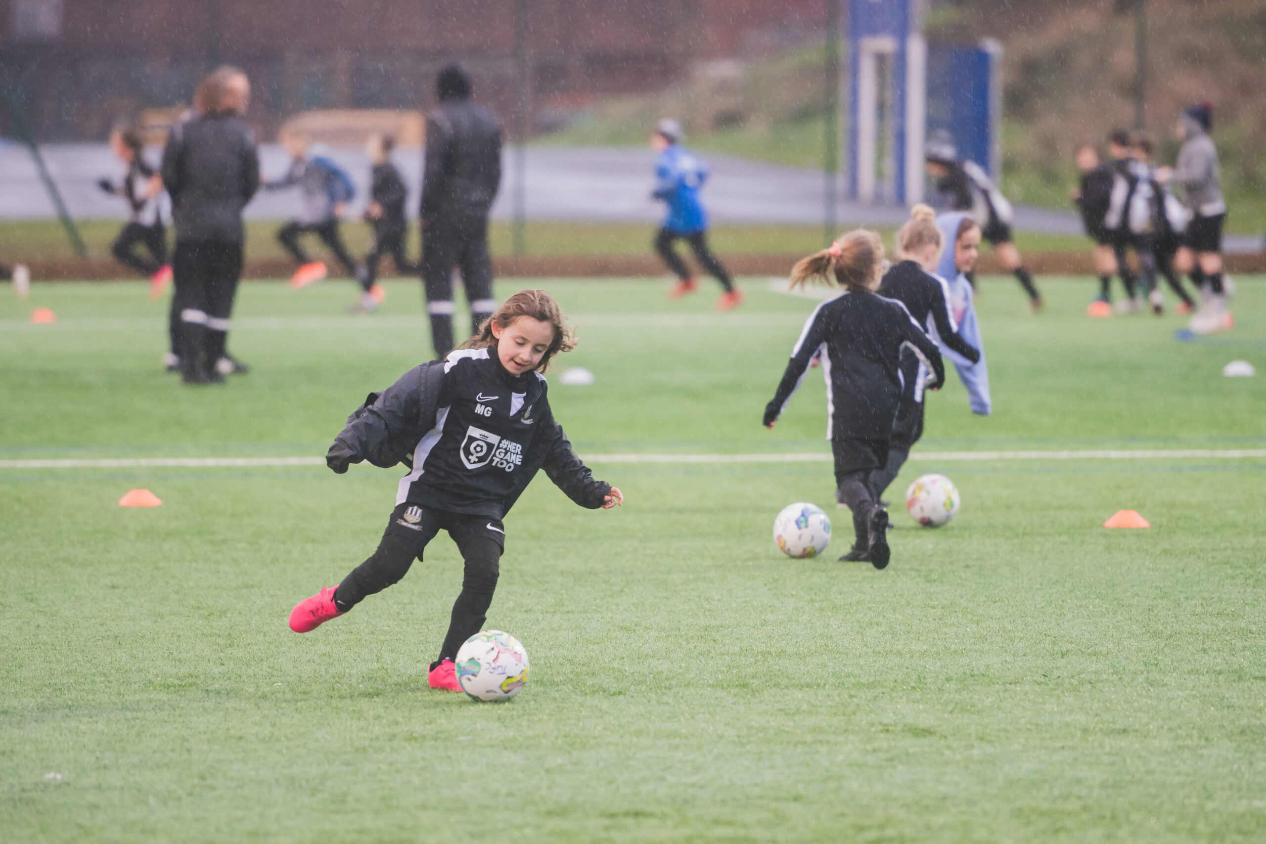 Young girls playing football on a pitch